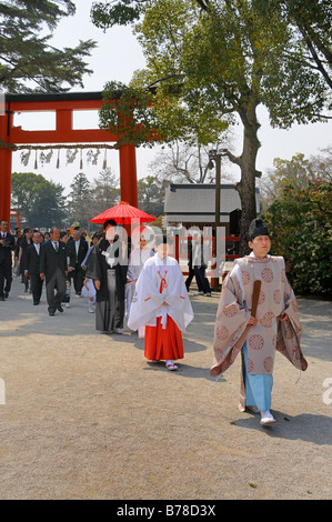 Brautpaar auf ihrem Weg zu einer Shinto Zeremonie mit einer Miko shrine Maiden und ein Shinto-Priester am Kamigamo Schrein, Kyoto, Stockfoto