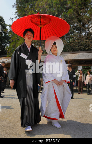 Japanische Hochzeitspaar tragen traditionelle Hochzeits-Kimonos, Braut trägt eine Haube, Bräutigam mit einem roten Sonnenschirm vor th Stockfoto