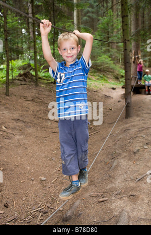 6-jähriger Junge balancieren auf einem Seil in einem Wald Stockfoto