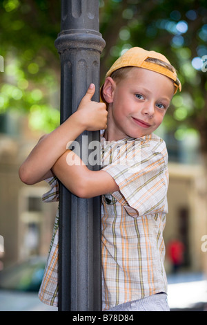 6-jähriger Junge klettern einen Laternenpfahl Stockfoto