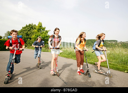 Schülerinnen und Schüler, jungen und Mädchen, Rollern, Reiten schieben Roller auf dem Weg von Schule, Basel, Schweiz, Europa Stockfoto