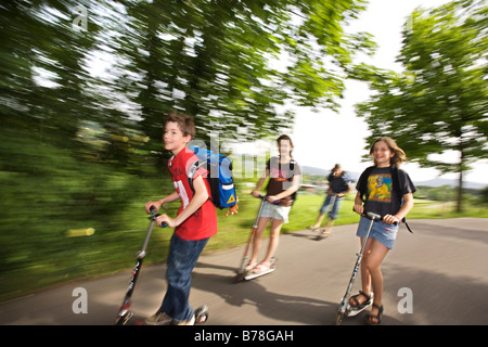 Schülerinnen und Schüler, jungen und Mädchen, Rollern, Reiten schieben Roller auf dem Weg von Schule, Basel, Schweiz, Europa Stockfoto