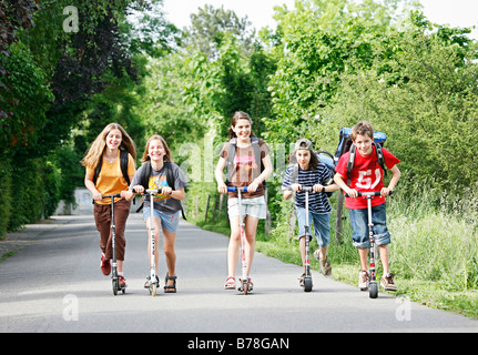 Schülerinnen und Schüler, jungen und Mädchen, Rollern, Reiten schieben Roller auf dem Weg von Schule, Basel, Schweiz, Europa Stockfoto