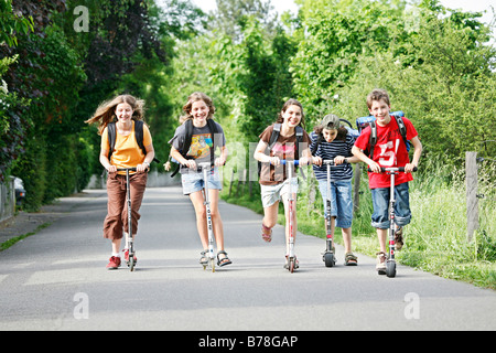 Schülerinnen und Schüler, jungen und Mädchen, Rollern, Reiten schieben Roller auf dem Weg von Schule, Basel, Schweiz, Europa Stockfoto