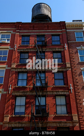 Wohnhaus mit Feuerwehr Drehleiter und hölzernen Wassertank auf dem Dach, Downtown New York City, USA Stockfoto