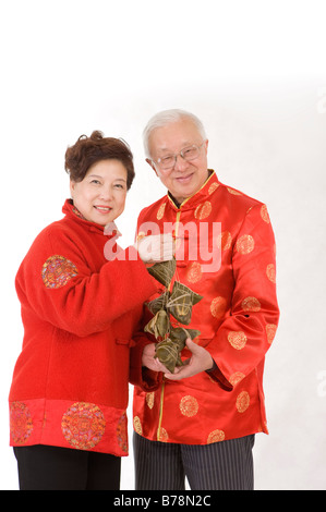 Älteres Ehepaar in traditioneller Kleidung hält Arborio-Reis Knödel und lächelt in die Kamera Stockfoto