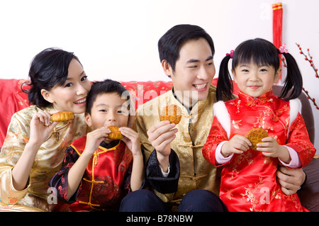 Junge Familie mit zwei Kindern halten Mondkuchen zusammen und lächelt glücklich Stockfoto