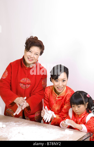 Zwei Frauen und ein kleines Mädchen in traditioneller Kleidung Knödel gemeinsam machen Stockfoto