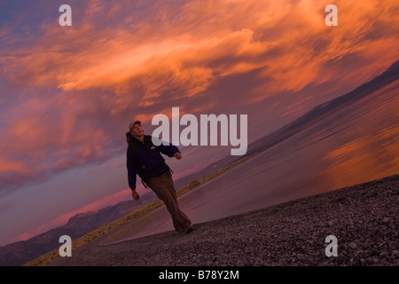 Ein Mann, Wandern entlang der Ufer des Mono Lake mit reflektierenden Wasser und Wolken in Kalifornien Stockfoto