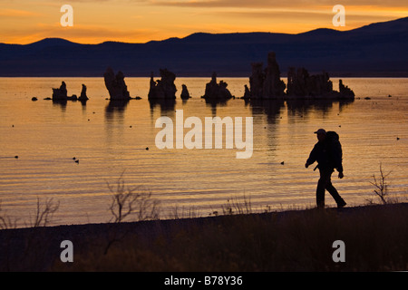 Ein Mann, Wandern entlang der Ufer des Mono Lake mit reflektierenden Wasser, Tuffstein Türme und Wolken in Kalifornien Stockfoto