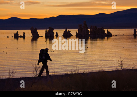 Ein Mann, Wandern entlang der Ufer des Mono Lake mit reflektierenden Wasser, Tuffstein Türme und Wolken in Kalifornien Stockfoto