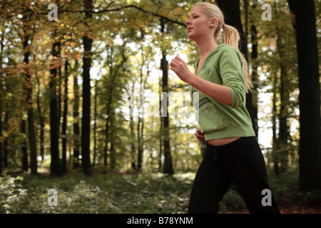 Junge blonde Frau im herbstlichen Wald joggen Stockfoto