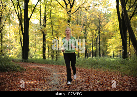 Junge blonde Frau im herbstlichen Wald joggen Stockfoto