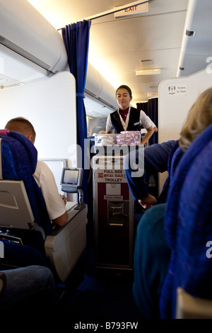 Flugbegleiterin servieren Mahlzeit für Passagiere in der Economy Class-Kabine, Flug mit British Airways Stockfoto