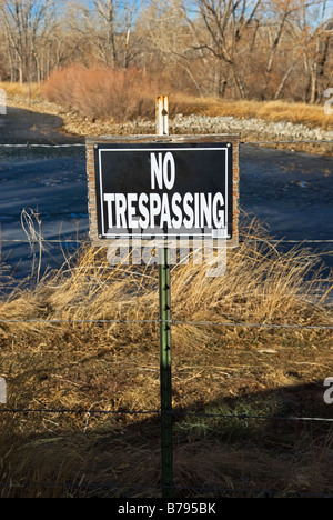 mittlere Nahaufnahme von NO TRESPASSING anmelden private Finca mit Stacheldrahtzaun und Wasser im Hintergrund Stockfoto