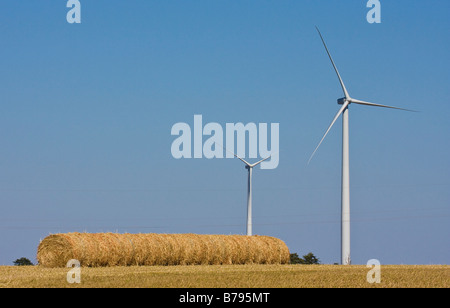 Windkraftanlagen stehen neben Heuballen In Kansas. Stockfoto