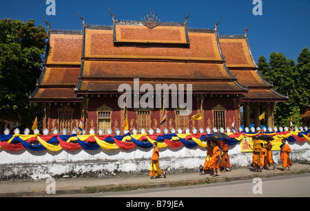 Buddhistische Mönche vorbei an der Ammer außerhalb Wat Sensoukharam in Luang Prabang. Eine Zeremonie soll im Wat stattfinden Stockfoto