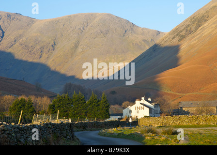 Mann und Frau zu Fuß in Richtung Wasdale Head Hotel mit Säule in der Ferne, Nationalpark Lake District, Cumbria, England UK Stockfoto