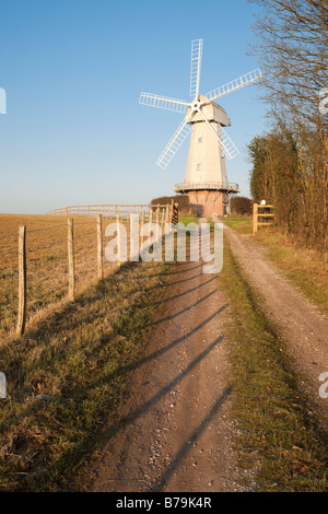 Alte Windmühle mit Weg und Zaun gegen klar blauen Himmel Stockfoto