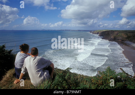 Paar sitzt auf Klippe oberhalb Druidston Haven, Pembrokeshire, Wales, UK, Europa Stockfoto