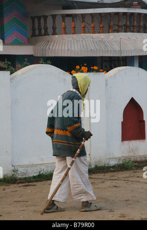Ein älterer Mann mit einem Stock zu Fuß durch Dorf Mokka in Madhya Pradesh, Indien früh am Weihnachtsmorgen Stockfoto