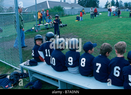 T-Ball-Spieler auf der Bank sitzen Stockfoto