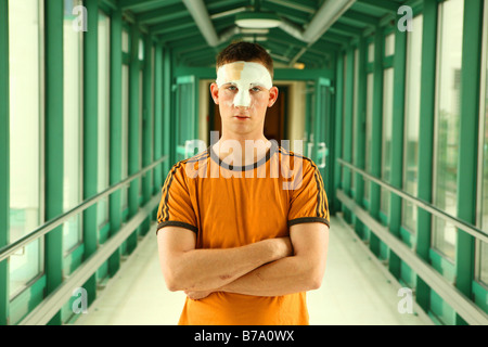 Junger Mann, ca. 22, auf dem Flur eines Krankenhauses mit einem Kopfverband Stockfoto