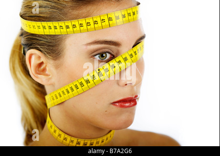 Junge Frau mit Maßband um den Kopf und Hals gewickelt Stockfoto