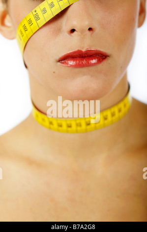 Junge Frau mit Maßband um den Kopf und Hals gewickelt Stockfoto