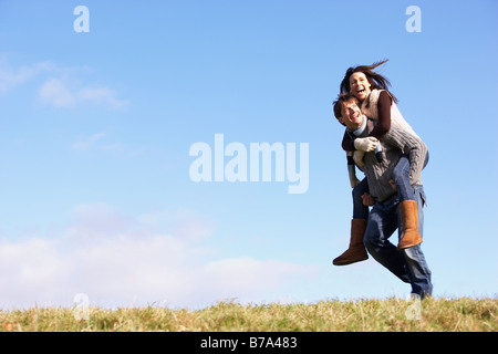 Mann seine Frau A Piggy Back Fahrt im Park Stockfoto