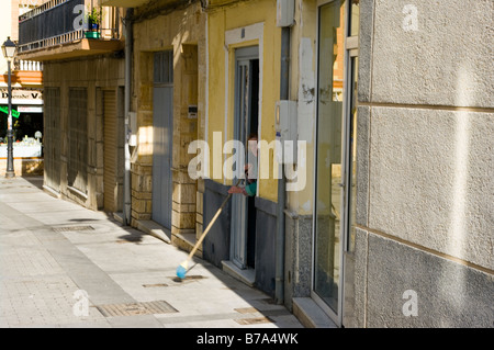 Frau kehren die Tür in eine schmale Seitenstraße Vera Almeria Spanien Stockfoto