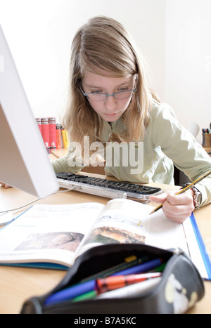 13 Jahre altes Mädchen am Computer ihre Hausaufgaben Stockfoto