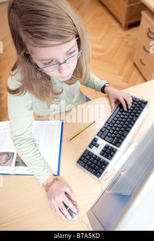 13 Jahre altes Mädchen am Computer ihre Hausaufgaben Stockfoto