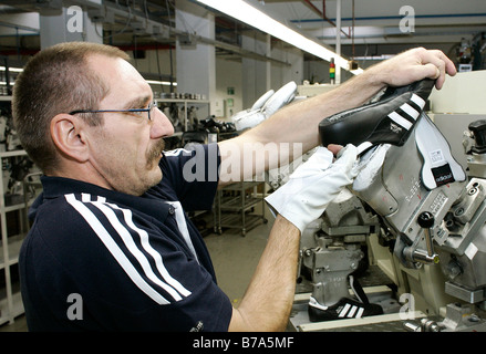 Arbeiter ziehen einen Schuh aus der Gießmaschine für das Hinzufügen von den Sohlen, Produktion von Copa Mundial Fußballschuhe in der Scheinfeld Stockfoto