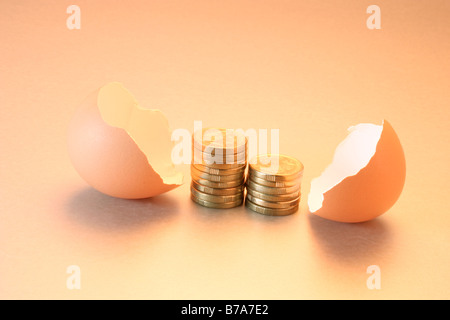 Münzen zwischen den gebrochenen Eierschalen Stockfoto