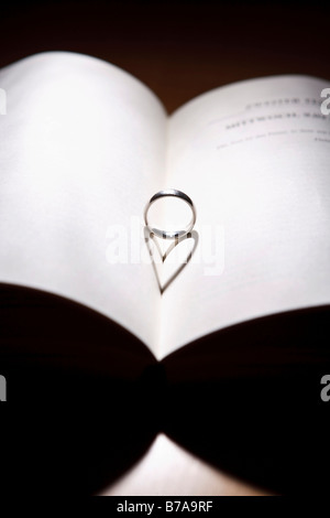 Ring mit einer herzförmigen Schatten auf ein offenes Buch