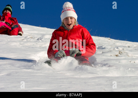 Zwei Mädchen, 9 und 12 Jahre alt, Reiten auf Schnee-Schieber, Dolomiten, Italien, Europa Stockfoto