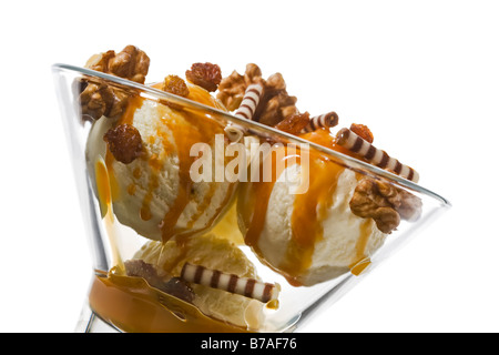 reiche Eis Dessert in Glasschale, dekoriert mit Caramel topping, Walnüsse, rollt von weißer und dunkler Schokolade, Rosinen Stockfoto