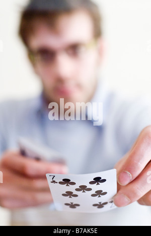 Junger Mann ausgeteilten Karten in einem Spiel von Poker - Schuss aus unter einem Glastisch Stockfoto