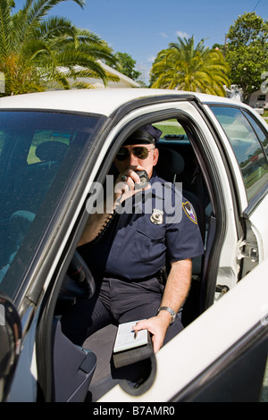 Polizist in seinem Auto in eine Lizenz-Nummer auf seinem Radio aufrufen Stockfoto