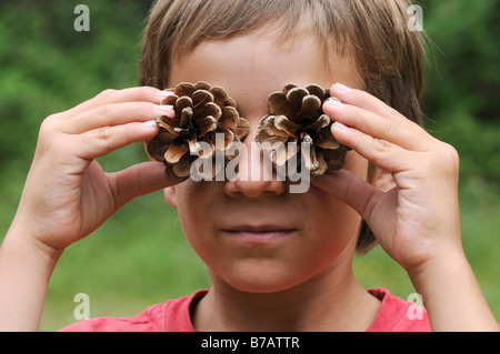 Junge mit Tannenzapfen vor Augen Stockfoto