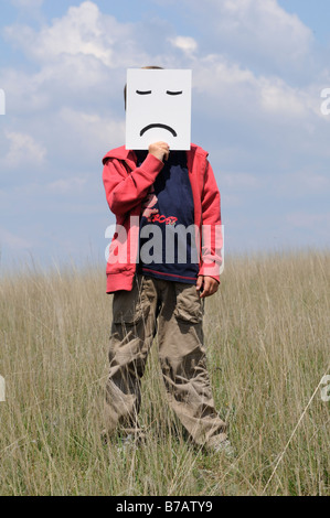 Junge im Feld Holding Stirnrunzeln Gesicht Stockfoto