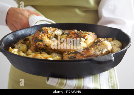 Nahaufnahme der gebratene Hähnchenschenkel, gerösteten Zwiebeln und Kartoffeln in Gusseisen Pfanne Stockfoto