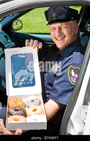 Polizist sitzt in seinem Streifenwagen mit einem Feld von donuts Stockfoto