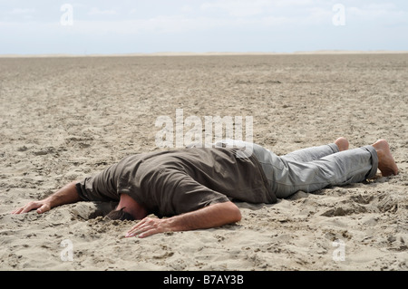 Mann mit Kopf im Sand vergraben Stockfoto