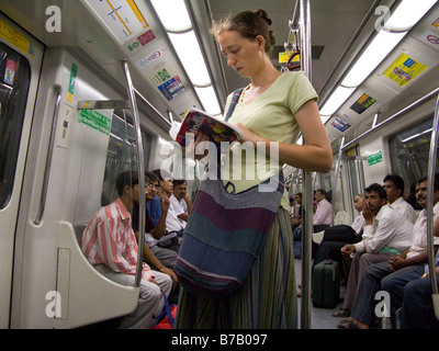 Eine westliche Frau Tourist auf eine gelbe Linie Rohr Zug Wagen Innenraum auf der Delhi Metro Rail System. Delhi, Indien. Stockfoto