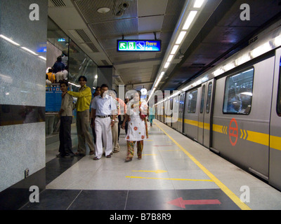 Eine gelbe Linie Zug, und einige abfliegenden indische Passagiere auf eine Plattform auf der Delhi Metro Rail System. Delhi. Indien. Stockfoto