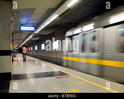 Ein gelbe Linie Zug bewegt sich weg von der Plattform auf der Delhi Metro Rail System. Delhi. Indien. Stockfoto