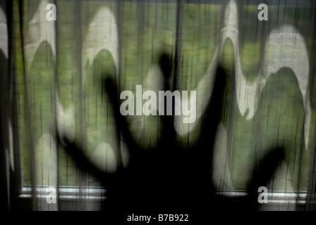 Eine Hand mit Fingern verbreiten aufgehalten, eine wellige Vorhang in einem Fenster Stockfoto