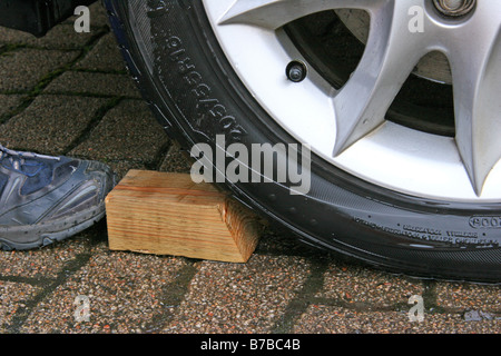 Holzblock eingekeilt auf Pkw-Reifen, Auto Rollen zu verhindern Stockfoto